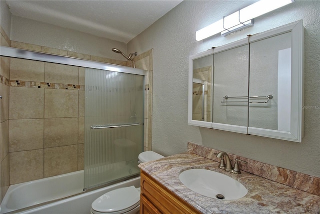 full bath with enclosed tub / shower combo, a textured wall, vanity, and toilet