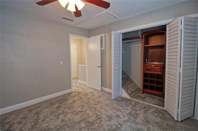 unfurnished bedroom with carpet floors, visible vents, a ceiling fan, baseboards, and attic access