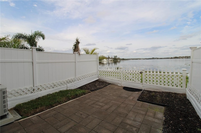 view of patio with a water view and fence