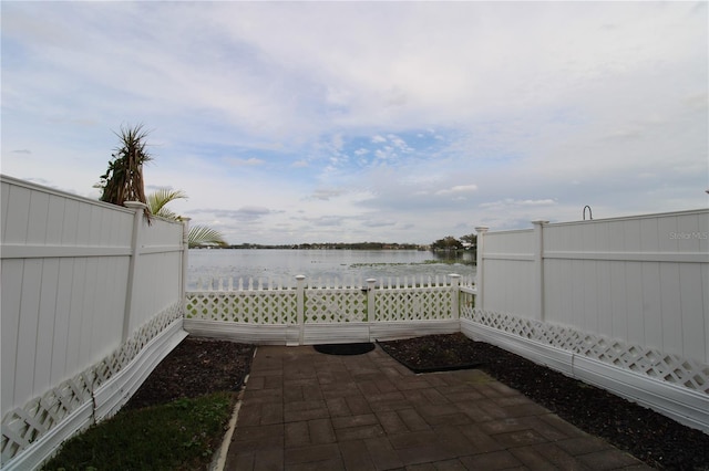 view of patio with a water view and fence