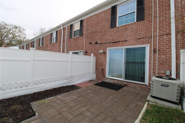 back of house with brick siding, a patio area, cooling unit, and fence