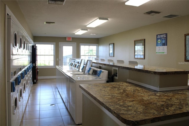 shared laundry area with light tile patterned floors, visible vents, stacked washer and clothes dryer, and washer and dryer