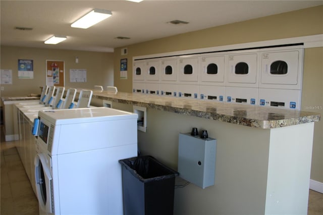 community laundry room featuring light tile patterned floors, separate washer and dryer, and stacked washer / drying machine