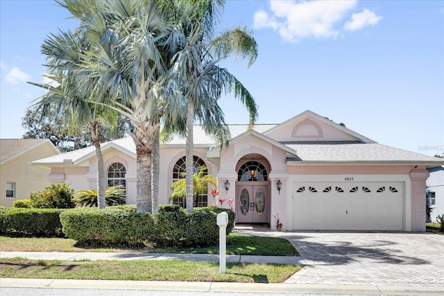 view of front of property with a garage, brick siding, and decorative driveway