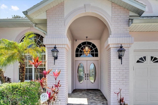 doorway to property featuring a garage, brick siding, and french doors