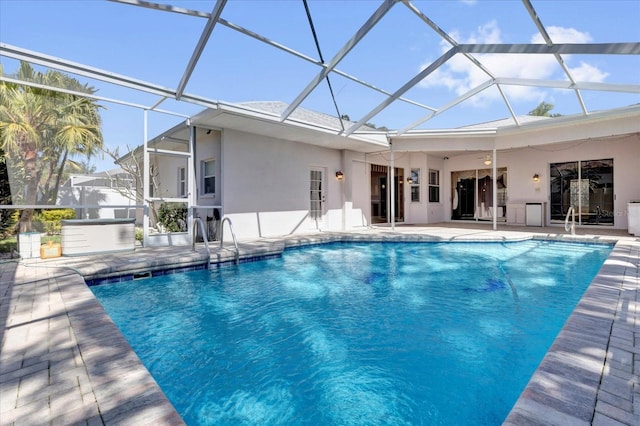 outdoor pool with a patio area, a jacuzzi, and glass enclosure