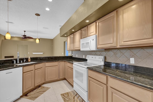 kitchen with decorative light fixtures, light tile patterned flooring, a sink, dark stone countertops, and white appliances