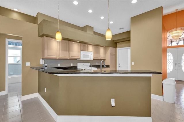 kitchen with dark stone counters, light tile patterned floors, range, and white microwave