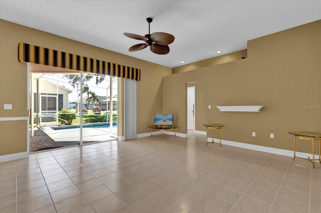 unfurnished room with ceiling fan, a textured ceiling, baseboards, and light tile patterned floors