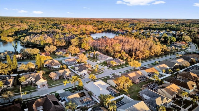 drone / aerial view featuring a water view, a wooded view, and a residential view