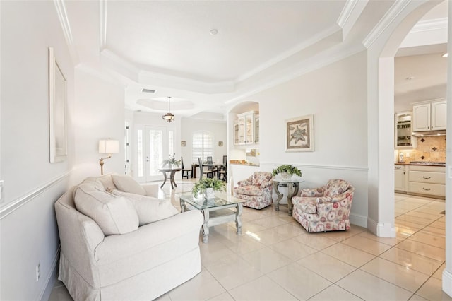 living area with arched walkways, visible vents, crown molding, and light tile patterned flooring