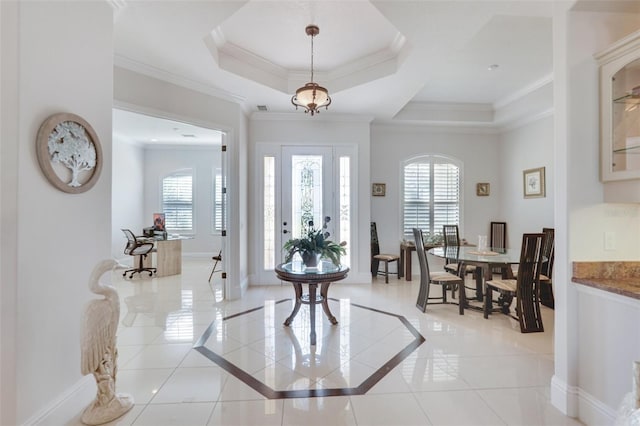 entrance foyer featuring light tile patterned floors, a tray ceiling, baseboards, and crown molding