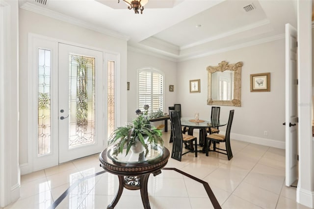 foyer entrance featuring visible vents, baseboards, crown molding, and a tray ceiling