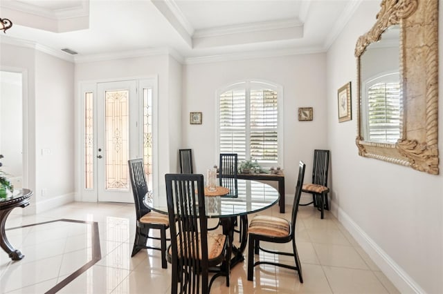 dining space with light tile patterned floors, baseboards, a raised ceiling, and crown molding