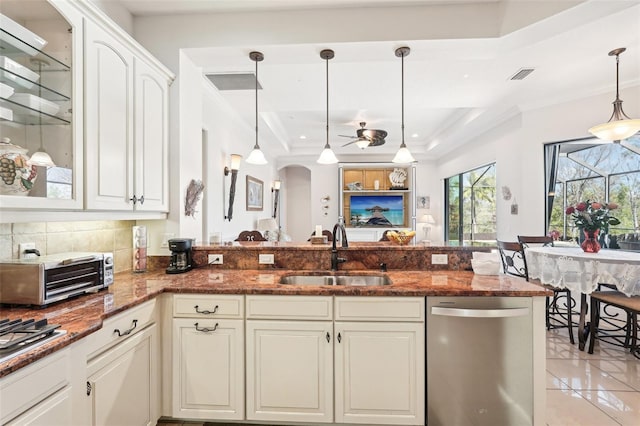 kitchen with dishwasher, dark stone counters, a tray ceiling, ornamental molding, and a sink