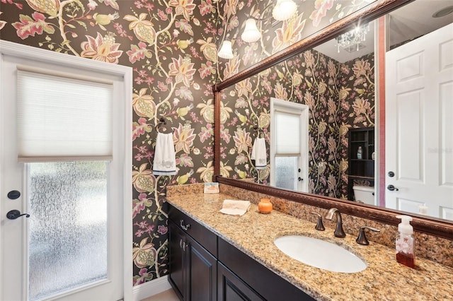 bathroom with vanity and wallpapered walls