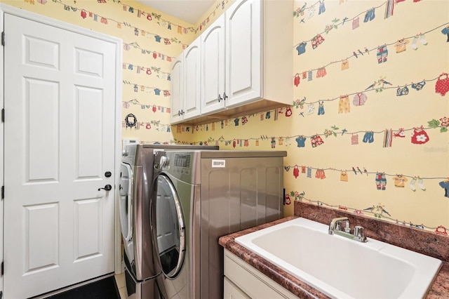 clothes washing area with washing machine and clothes dryer, cabinet space, wallpapered walls, and a sink