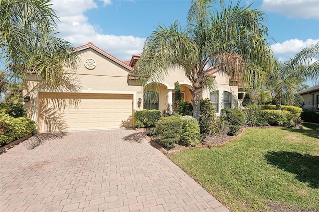 mediterranean / spanish-style house with a front yard, decorative driveway, an attached garage, and stucco siding