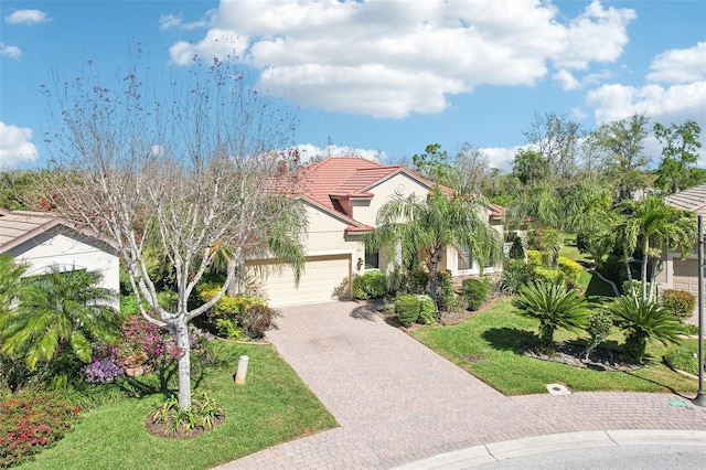 mediterranean / spanish house featuring a front yard, stucco siding, a garage, a tile roof, and decorative driveway