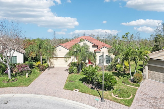 mediterranean / spanish-style house with a tiled roof, a front yard, stucco siding, decorative driveway, and a garage