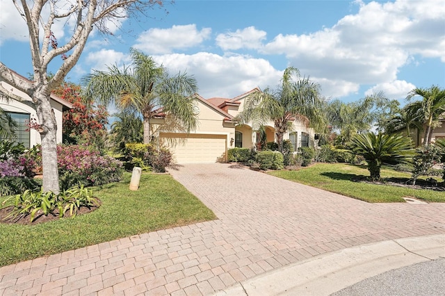 mediterranean / spanish house with a front yard, decorative driveway, a garage, and stucco siding