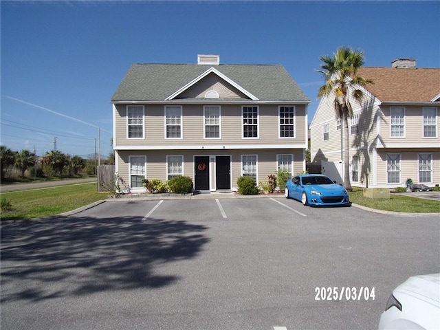 view of front of property featuring uncovered parking and roof with shingles