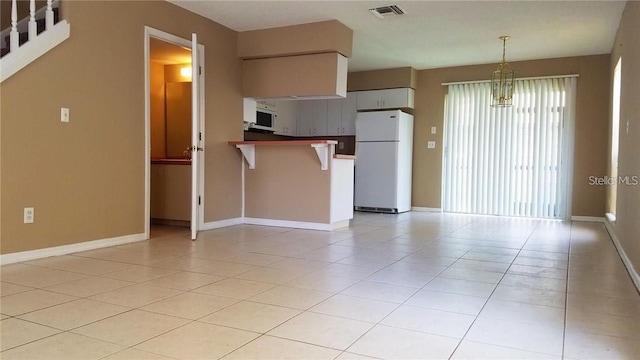 kitchen featuring visible vents, white appliances, light tile patterned flooring, and a peninsula