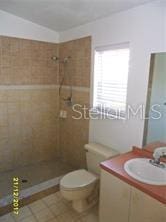 full bathroom with tiled shower, mail area, vanity, and toilet