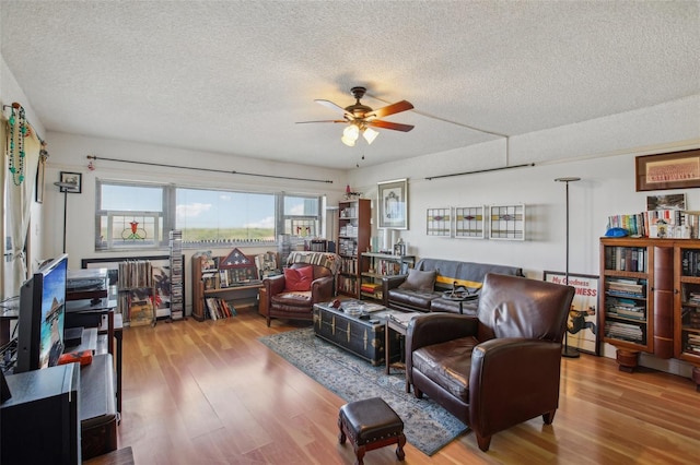 living room featuring a textured ceiling, ceiling fan, and wood finished floors