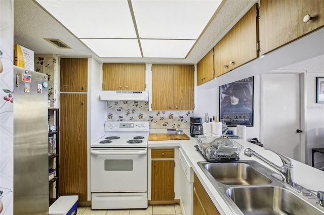 kitchen with visible vents, under cabinet range hood, a sink, white appliances, and light countertops