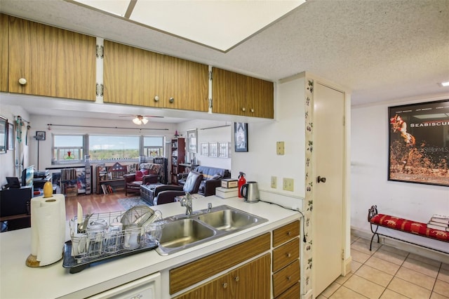 kitchen featuring light tile patterned floors, a sink, light countertops, a textured ceiling, and open floor plan