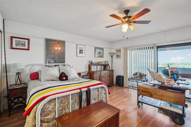 bedroom with ceiling fan, wood finished floors, and a textured ceiling