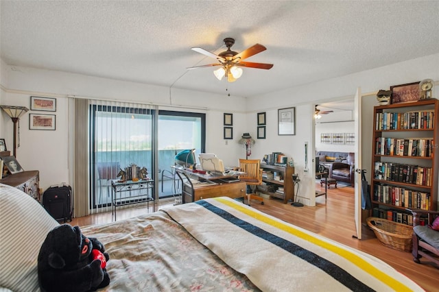 bedroom with access to exterior, wood finished floors, and a textured ceiling