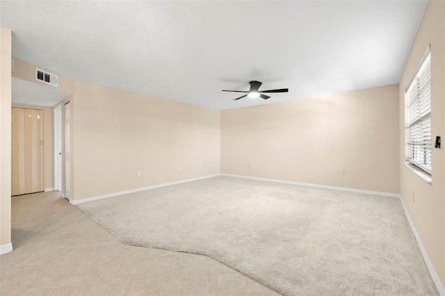 unfurnished room with light carpet, visible vents, a ceiling fan, and baseboards