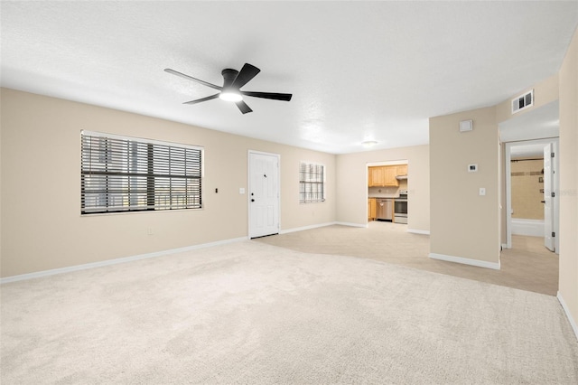 unfurnished living room with visible vents, light carpet, a ceiling fan, a textured ceiling, and baseboards