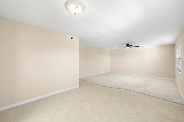 empty room with visible vents, baseboards, a textured ceiling, and a ceiling fan