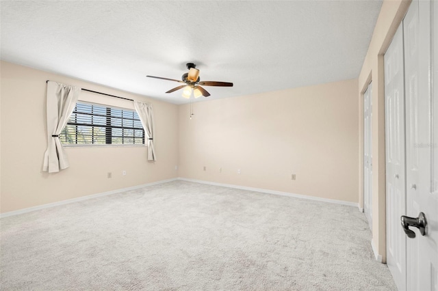 unfurnished bedroom with baseboards, light carpet, a textured ceiling, and a ceiling fan