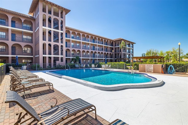 community pool with a patio and fence