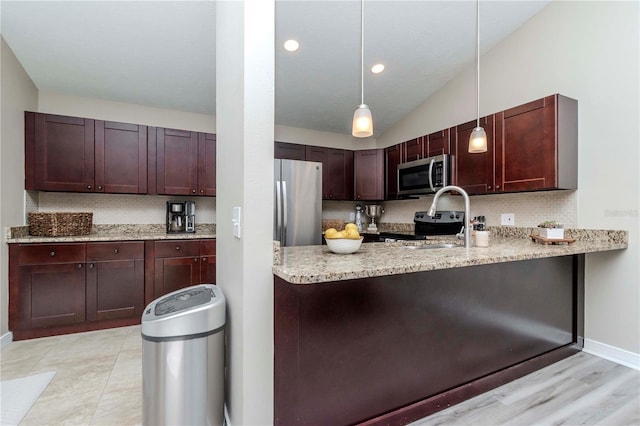 14501 Brambie Ct, Tampa, FL 33624 - kitchen featuring a peninsula, appliances with stainless steel finishes, lofted ceiling, light stone counters, and pendant lighting