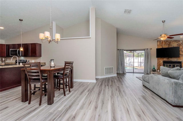 14501 Brambie Ct, Tampa, FL 33624 - dining space with a stone fireplace, ceiling fan with notable chandelier, visible vents, and light wood-style flooring