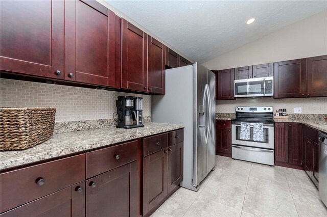 14501 Brambie Ct, Tampa, FL 33624 - kitchen featuring lofted ceiling, light tile patterned flooring, light stone counters, dark brown cabinets, and appliances with stainless steel finishes