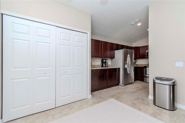 14501 Brambie Ct, Tampa, FL 33624 - kitchen featuring visible vents, light stone countertops, stainless steel appliances, dark brown cabinets, and lofted ceiling