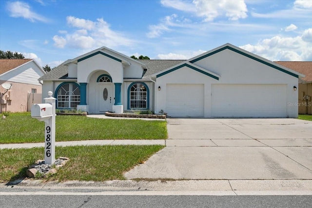 ranch-style house with an attached garage, concrete driveway, roof with shingles, stucco siding, and a front lawn