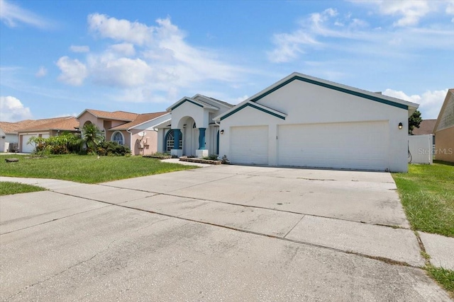 view of front facade with a garage, driveway, a front yard, and stucco siding