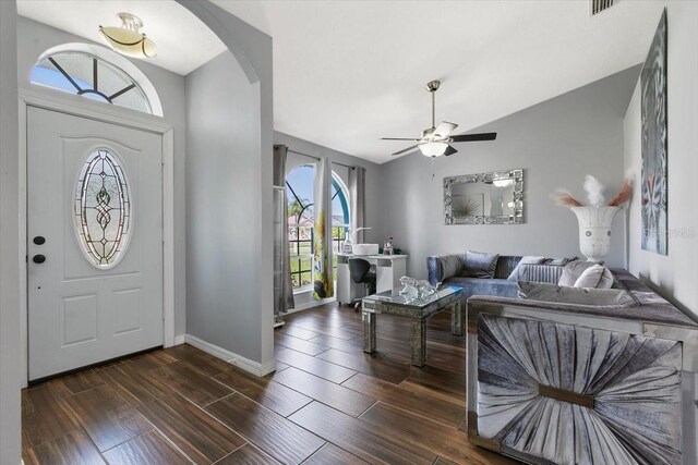 entryway with baseboards, arched walkways, a ceiling fan, dark wood-style floors, and vaulted ceiling