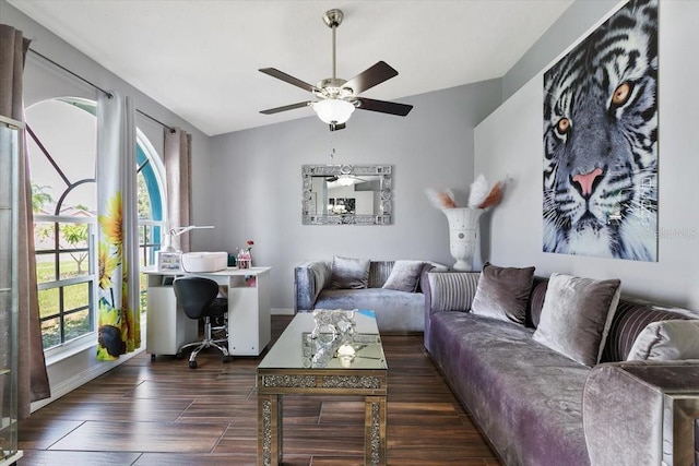 living room with a ceiling fan, vaulted ceiling, baseboards, and wood finished floors