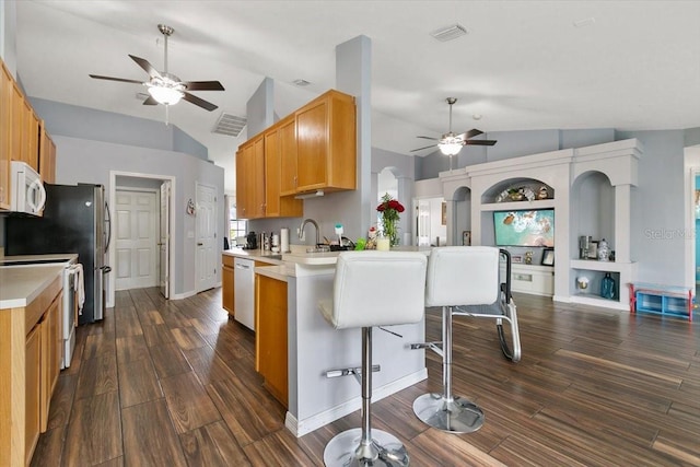 kitchen with white appliances, visible vents, a kitchen breakfast bar, a peninsula, and light countertops