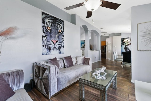 living room featuring arched walkways, ceiling fan, baseboards, and wood finished floors