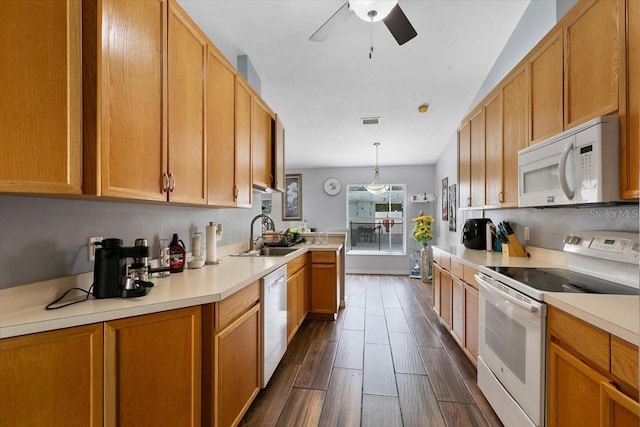 kitchen featuring white appliances, dark wood finished floors, light countertops, pendant lighting, and a sink