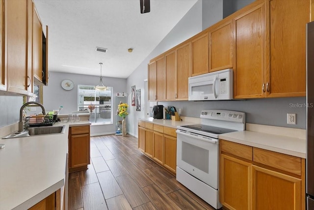 kitchen featuring white appliances, dark wood-style flooring, a sink, light countertops, and pendant lighting